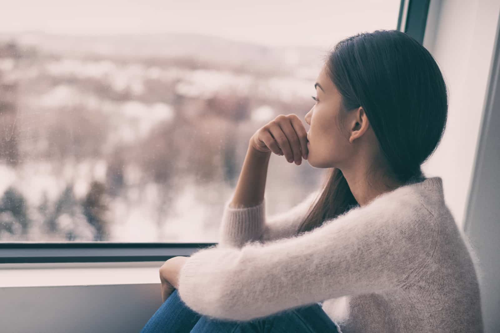 young girl looking through window