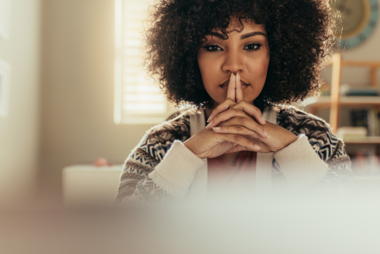 a pensive woman with frizzy hair is sitting at the table
