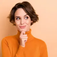 woman in an orange sweater thinking