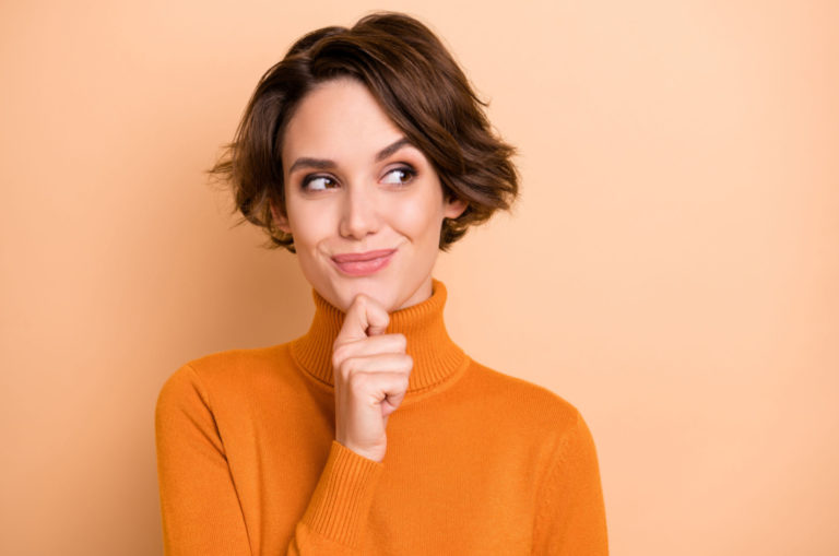 woman in an orange sweater thinking