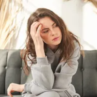 pensive woman sitting on the couch