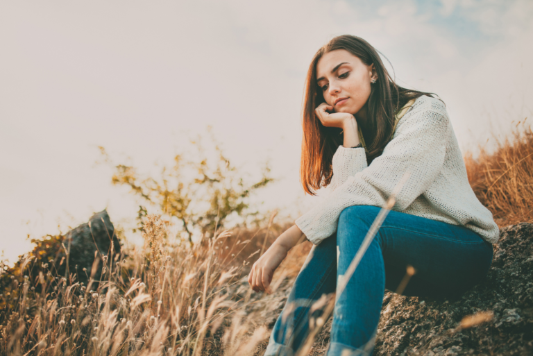 pensive woman sitting on the grass