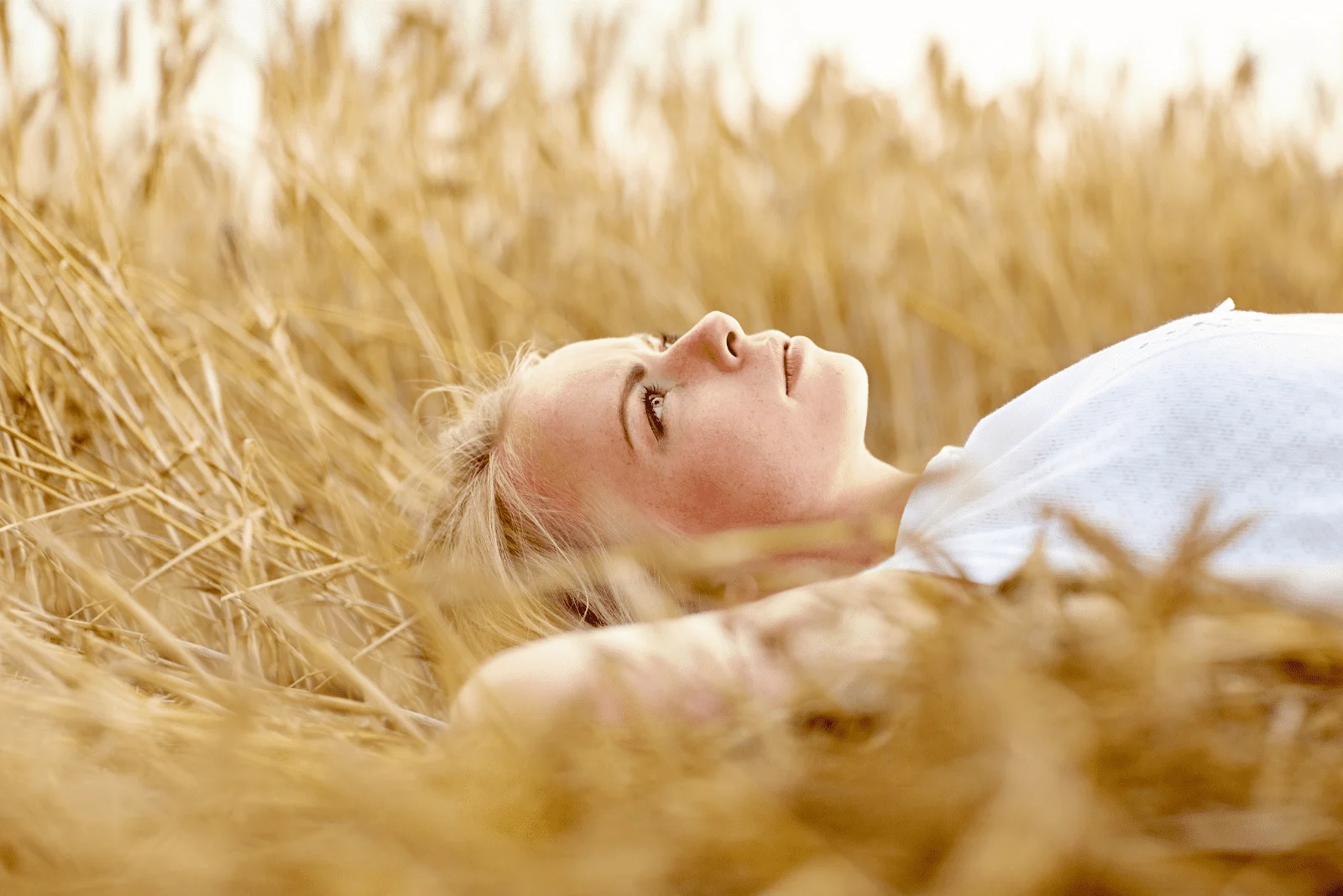 en vakker kvinne ligger i marken og ser på himmelen