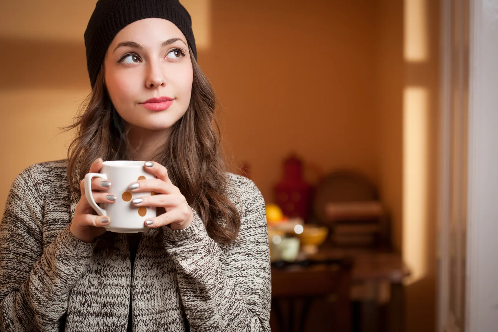 a beautiful woman with a cap on her head holds a cup in her hand