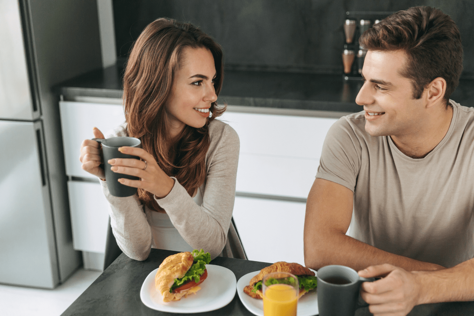 a man and a woman are sitting in the kitchen and talking 