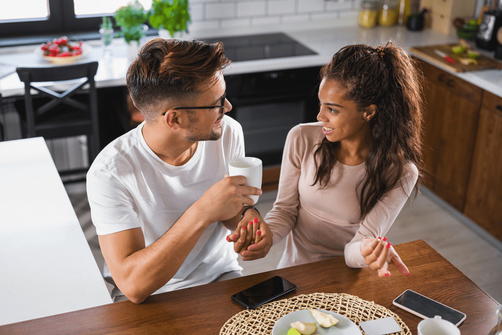 a man and a woman are sitting in the kitchen and talking