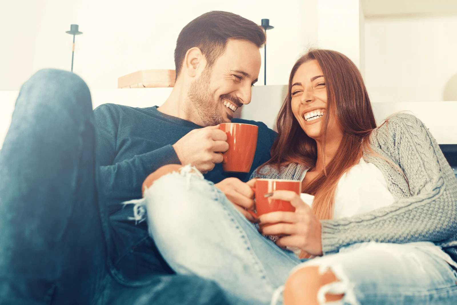 a man and a woman are sitting, laughing and drinking coffee