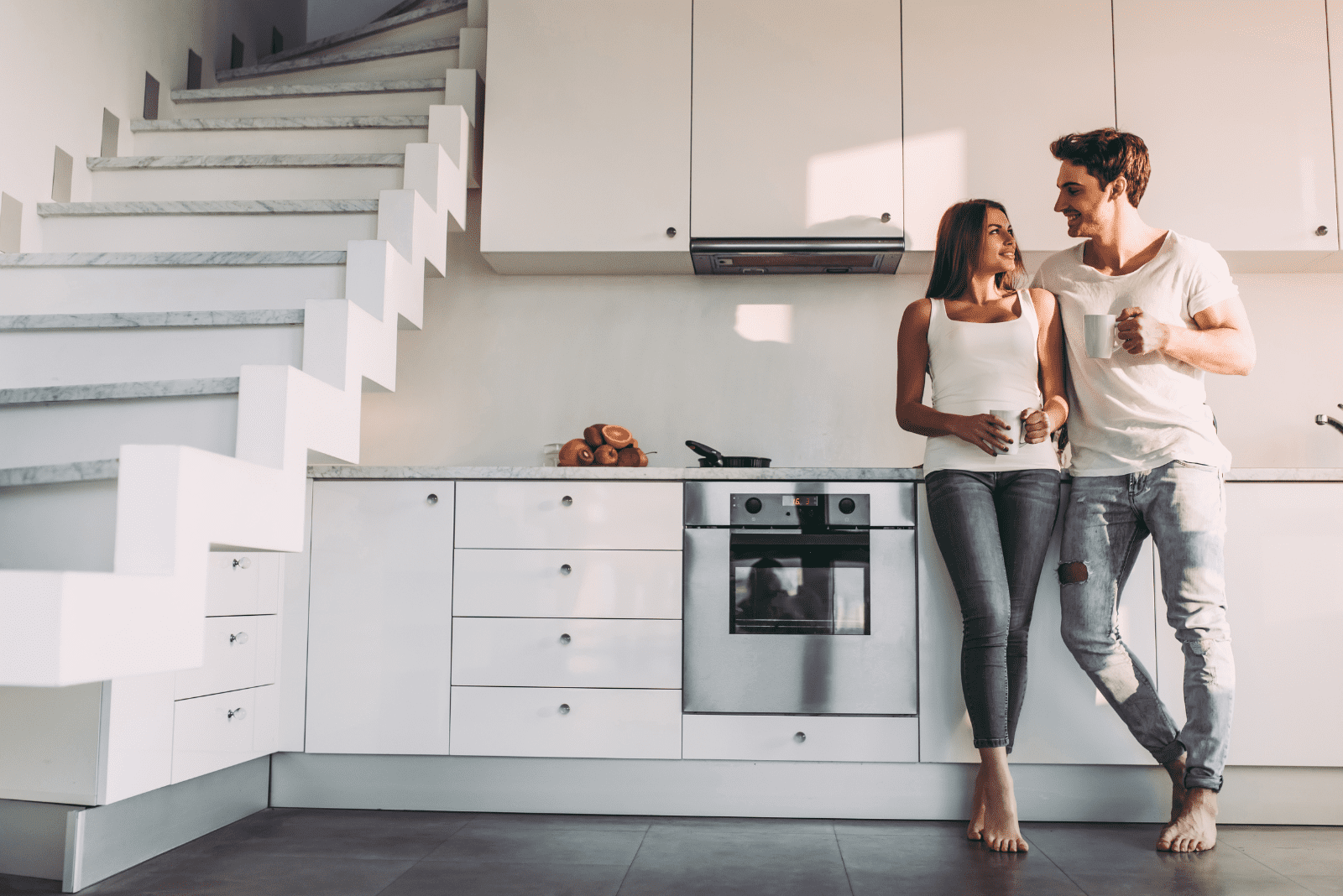 a man and a woman are standing next to each other leaning against the kitchen