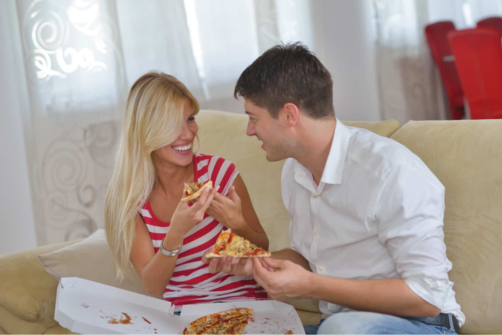 giovane coppia felice mangia pizza fresca a casa rilassandosi e guardando la tv