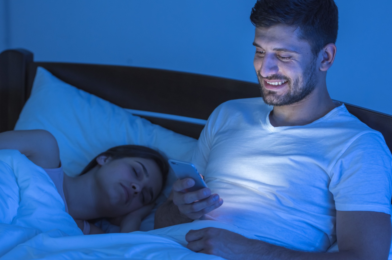 hombre enviando mensajes de texto en la cama