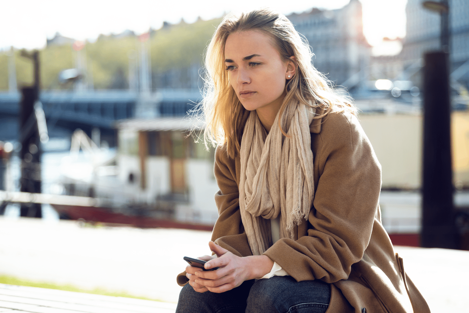 pensive woman sits and holds a mobile phone in her hand