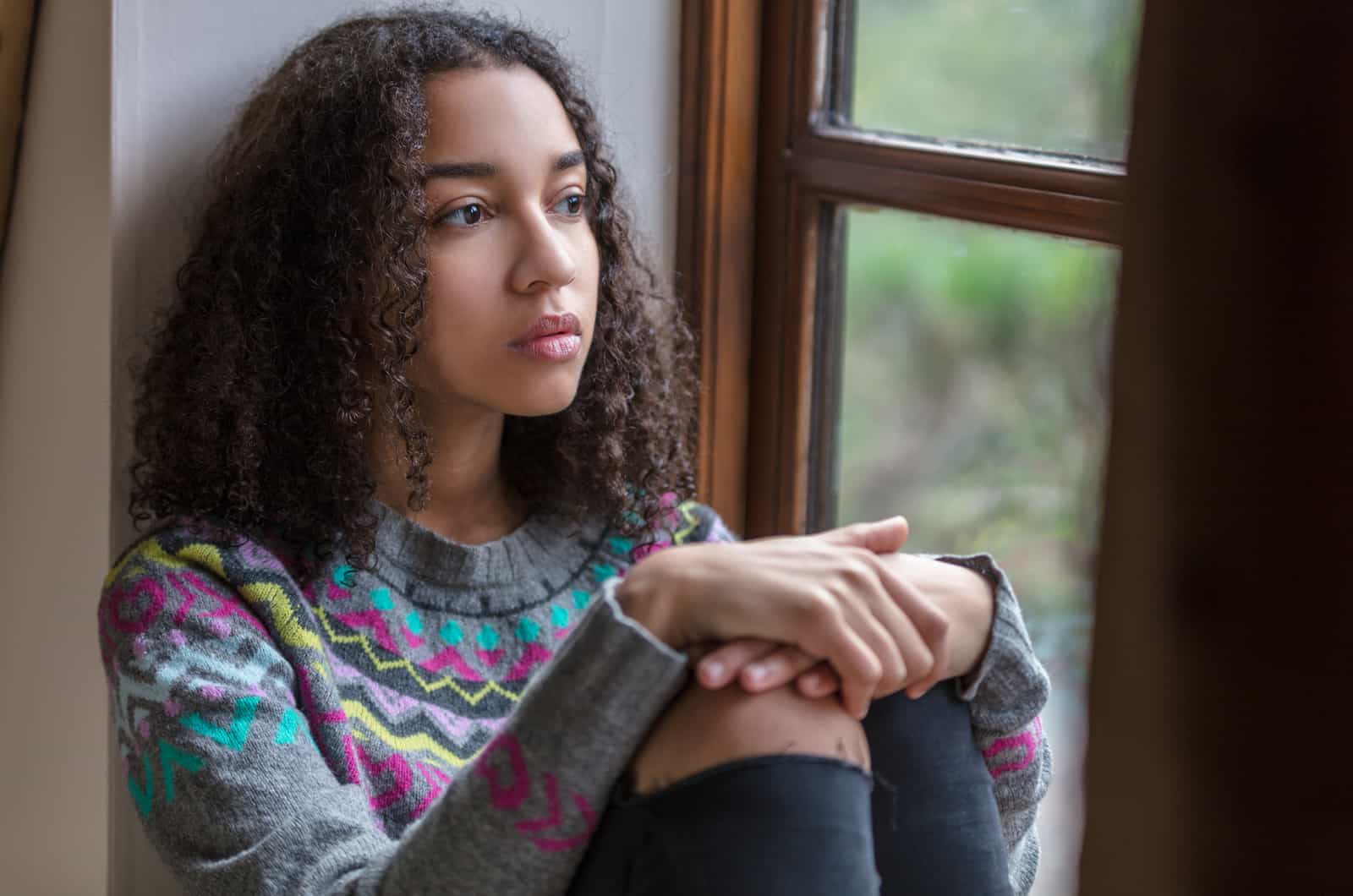 sad woman sitting by a window