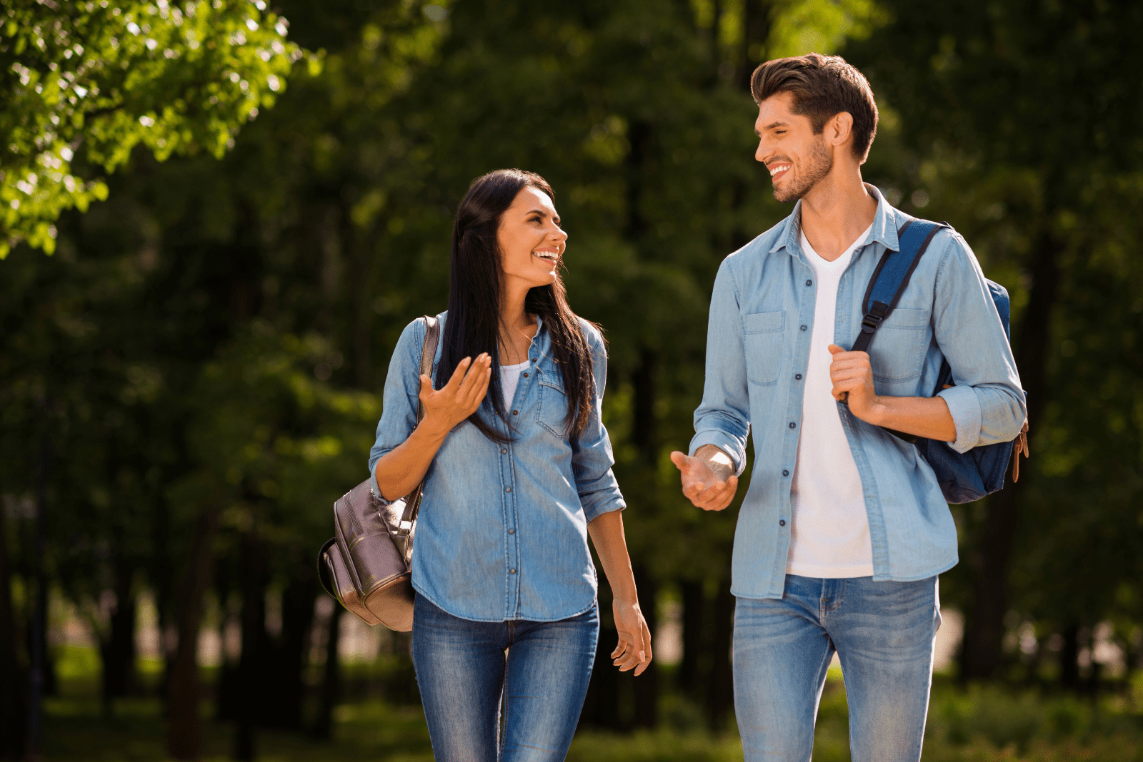 Um homem e uma mulher sorridentes estão a passear no parque e a conversar