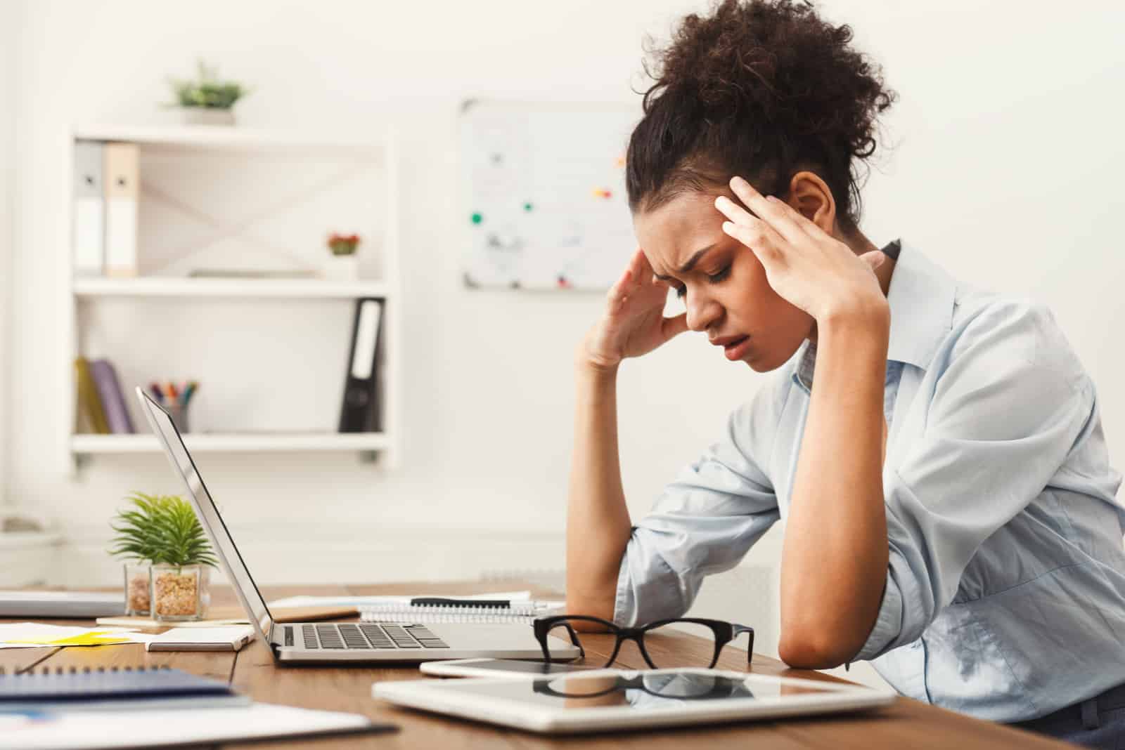 mujer estresada sentada en la oficina con dolor de cabeza