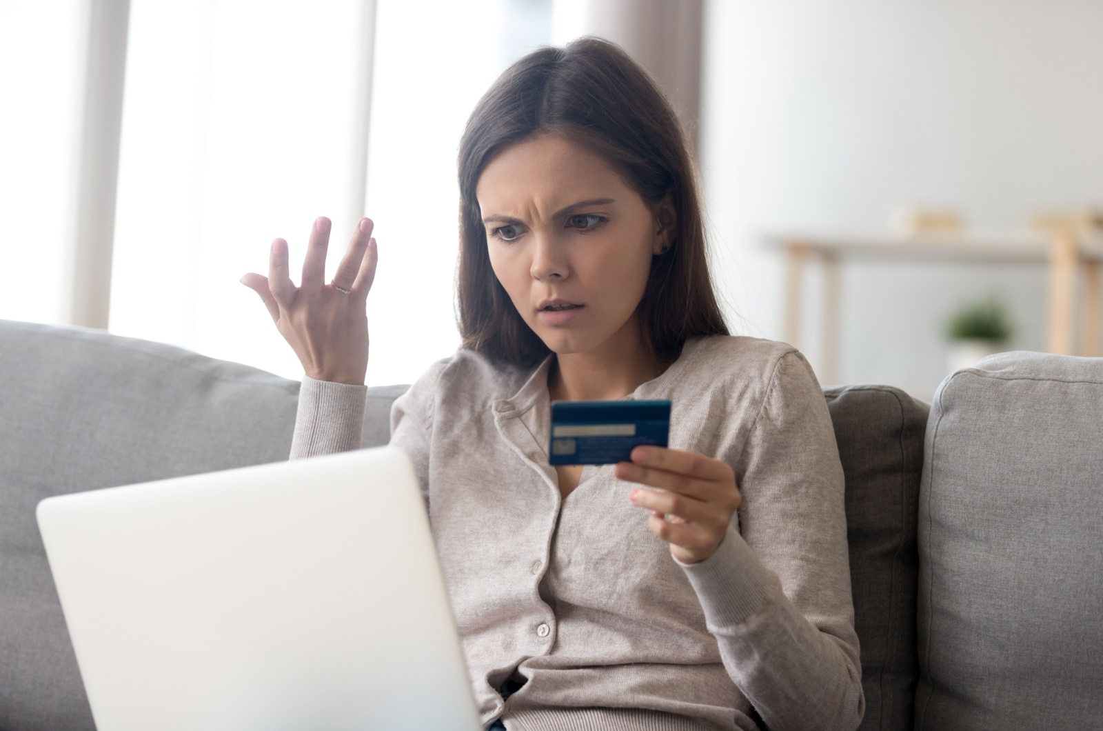 mujer disgustada con una tarjeta de crédito en la mano