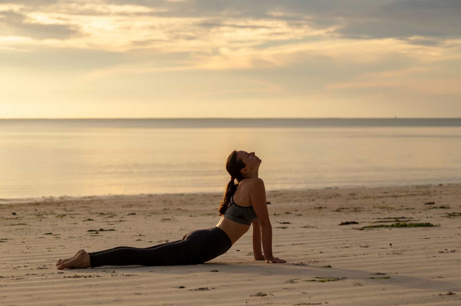 donna che fa yoga in spiaggia