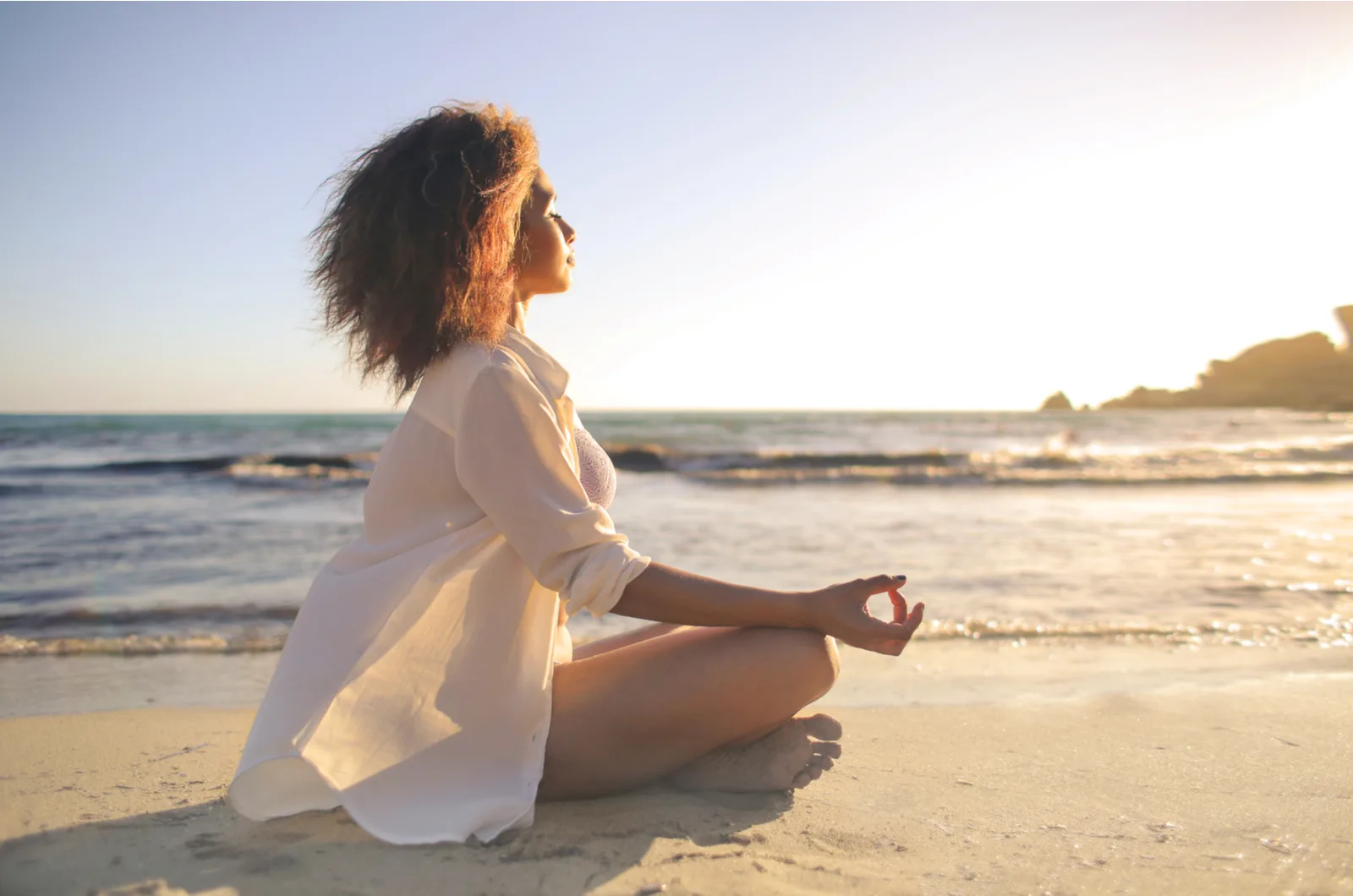woman meditating on beach in sunset