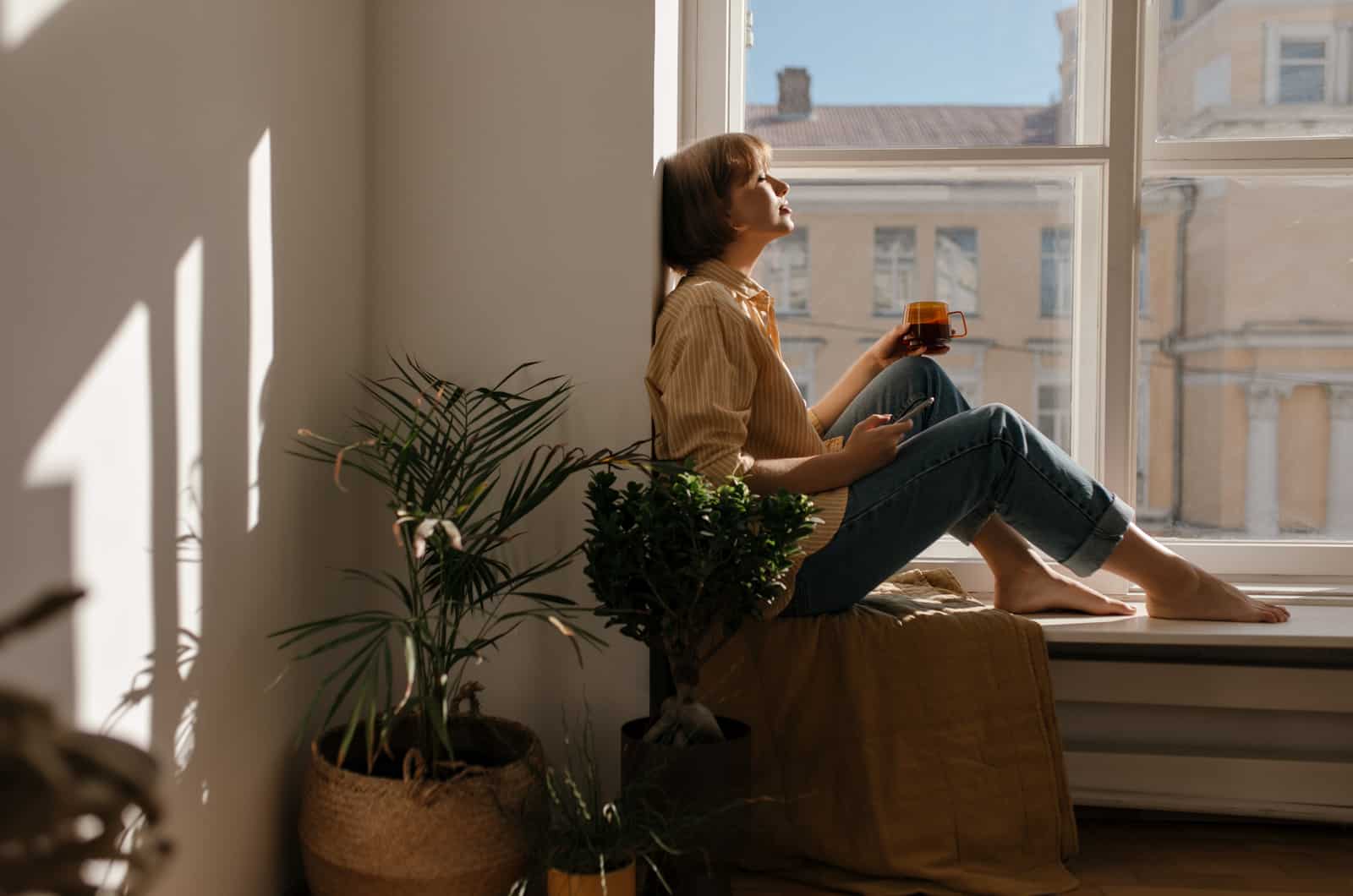 mujer sentada mirando por la ventana