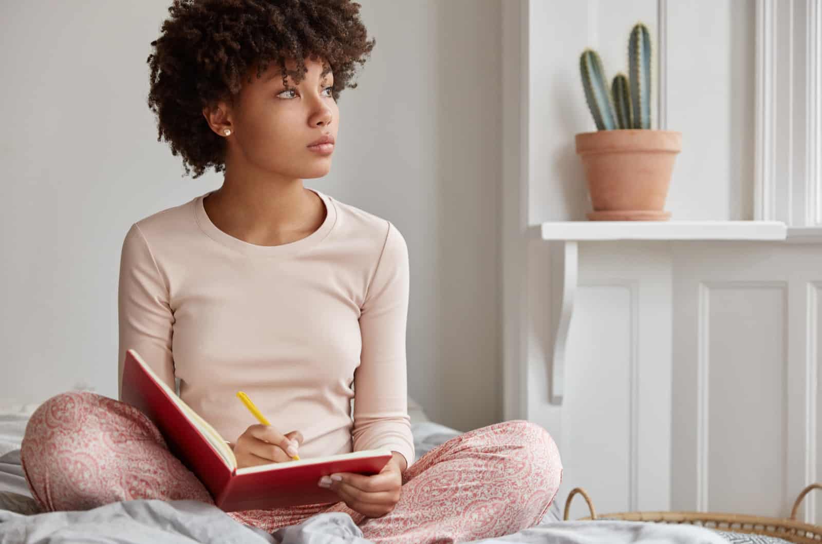 woman writing in diary while sititng on bed