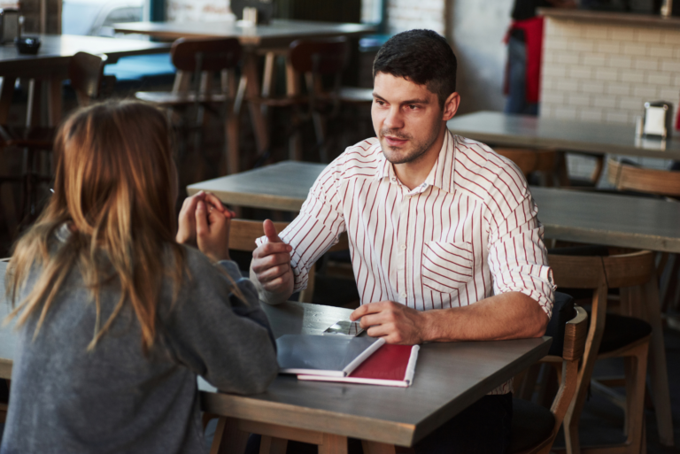 a man and a woman are sitting at the table and talking