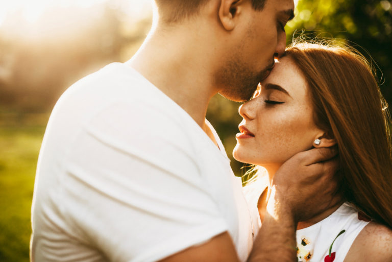 man kisses woman on the forehead