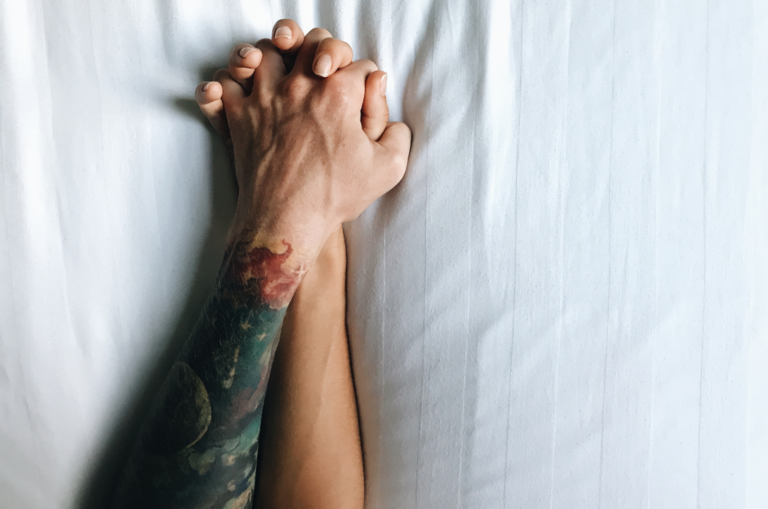 coppia che si tiene per mano a letto