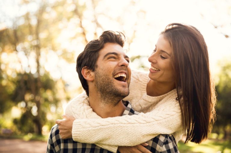 Happy couple in the park looking at each other and laughing