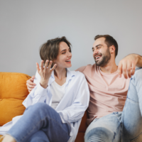 smiling loving couple sitting on the couch and talking