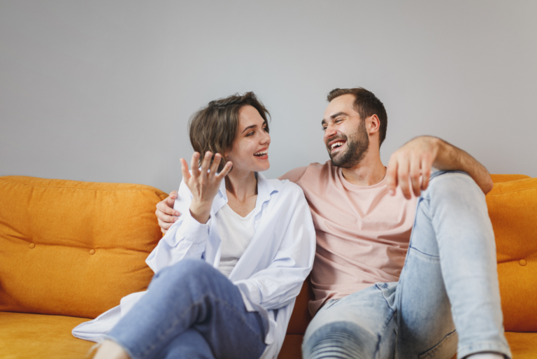 smiling loving couple sitting on the couch and talking