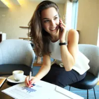 smiling woman sits on the phone and works