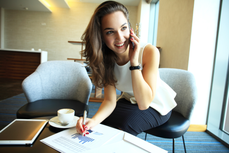 smiling woman sits on the phone and works