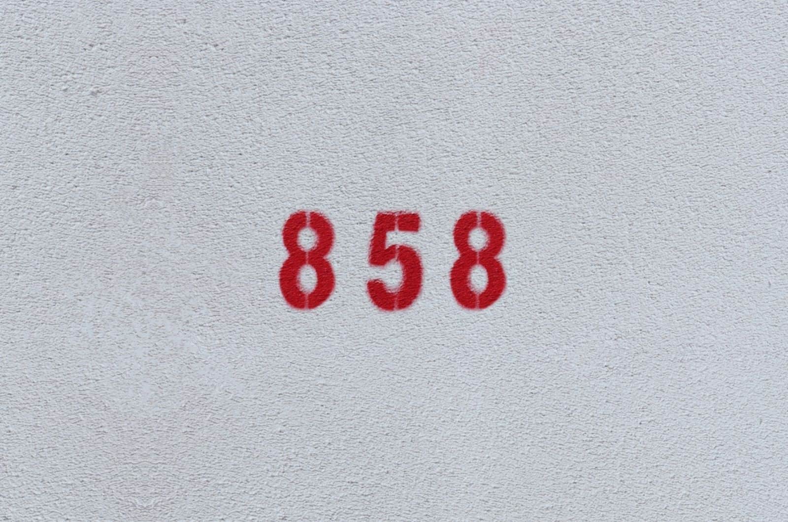 Número vermelho 858 na parede branca