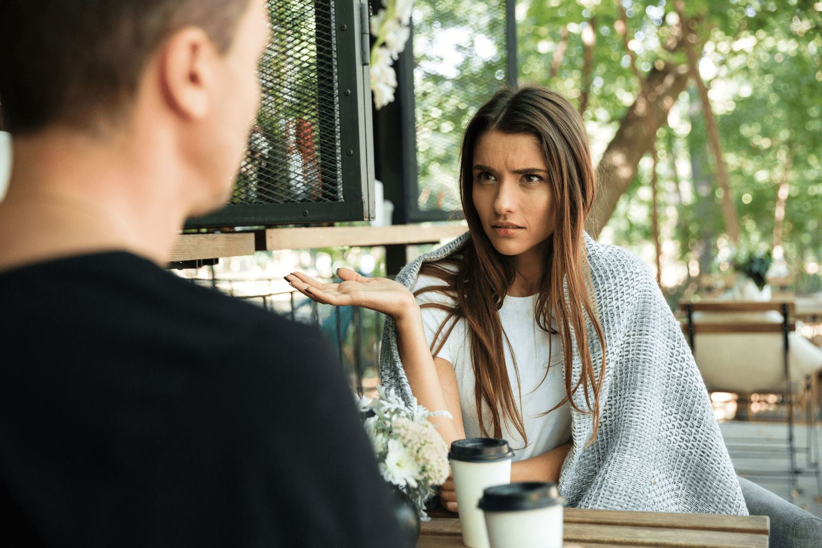 uma mulher desiludida, com longos cabelos castanhos, está a falar com um homem