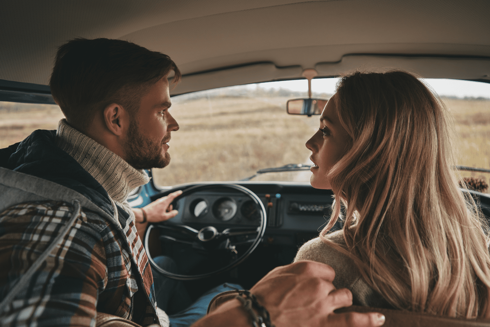 um homem e uma mulher estão sentados num carro e conversam