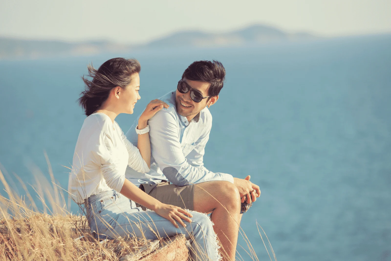 a man and a woman are sitting on a rock and talking