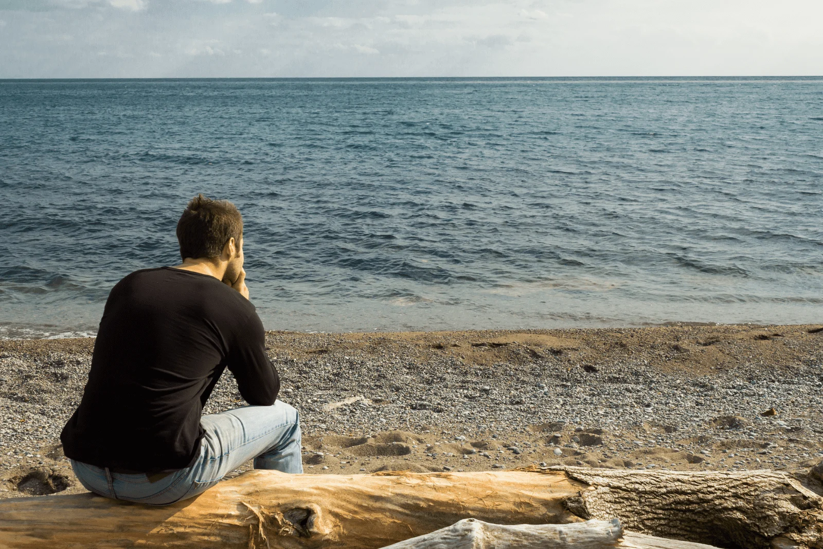 a man is sitting by the sea