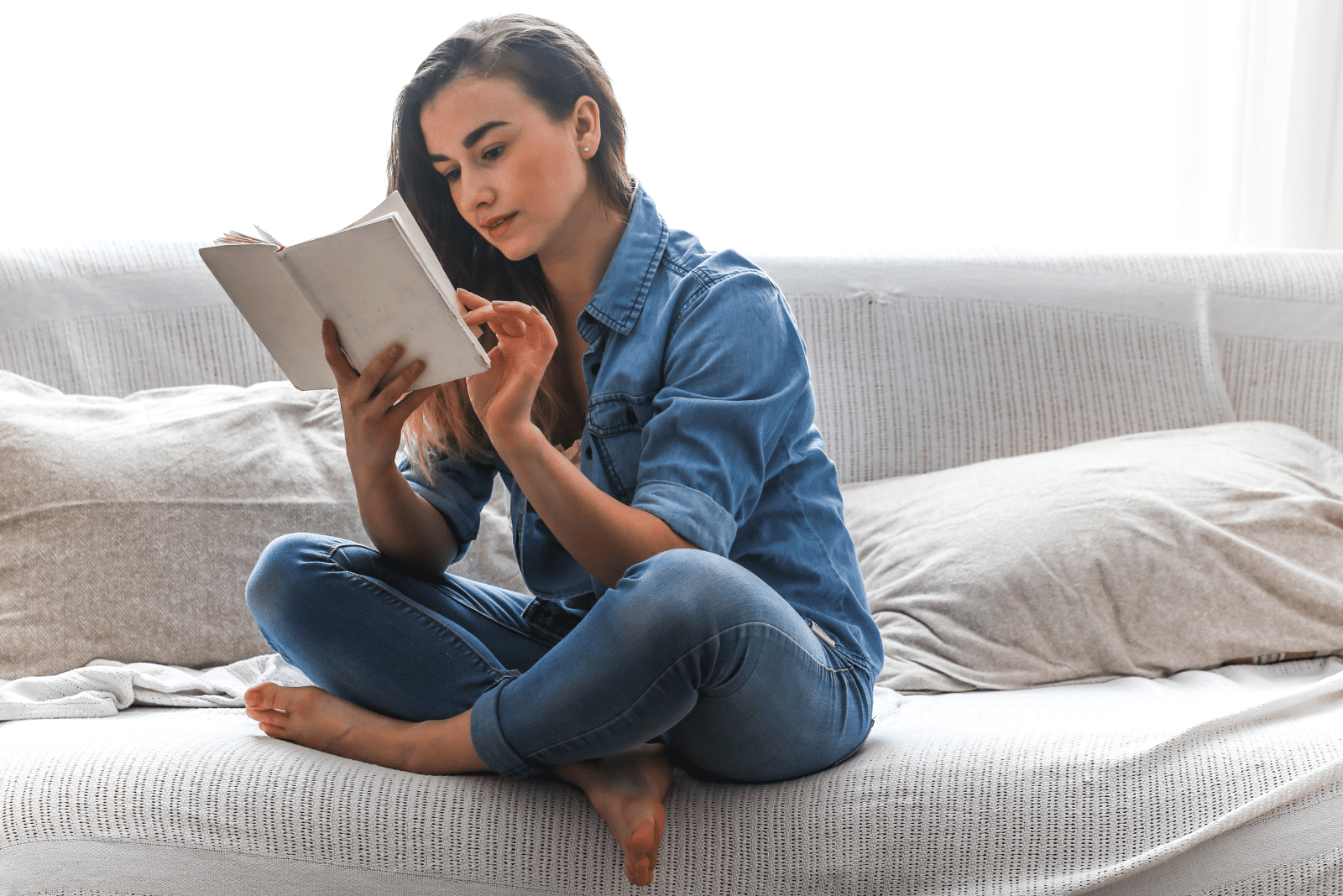 a woman is sitting on the couch and reading a book