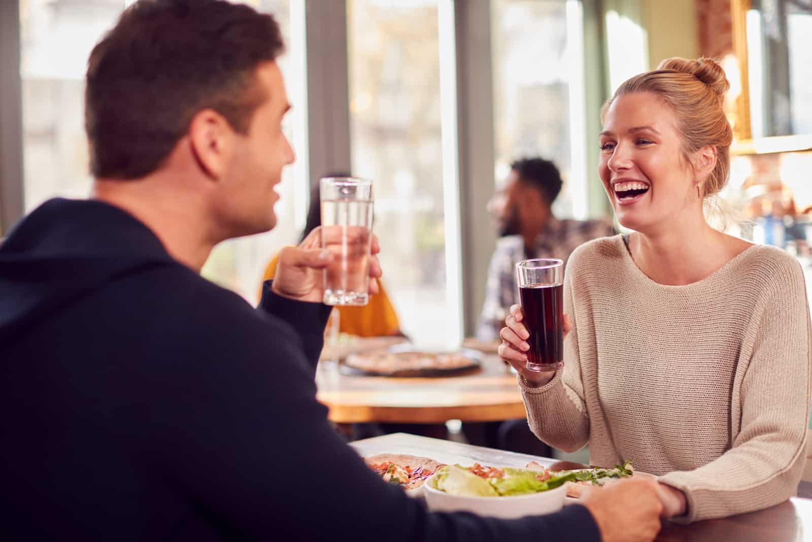 pareja sonriente en la fecha disfrutando de pizza en el restaurante juntos