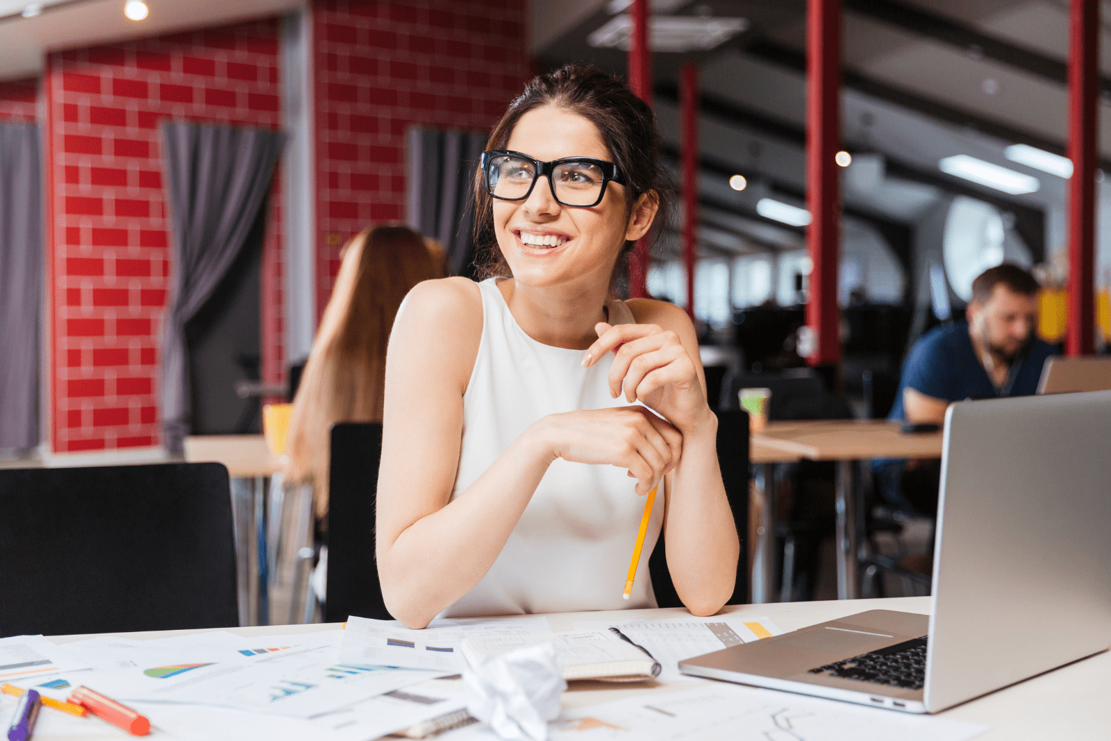 mujer sonriente con gafas se sienta en la oficina en la mesa
