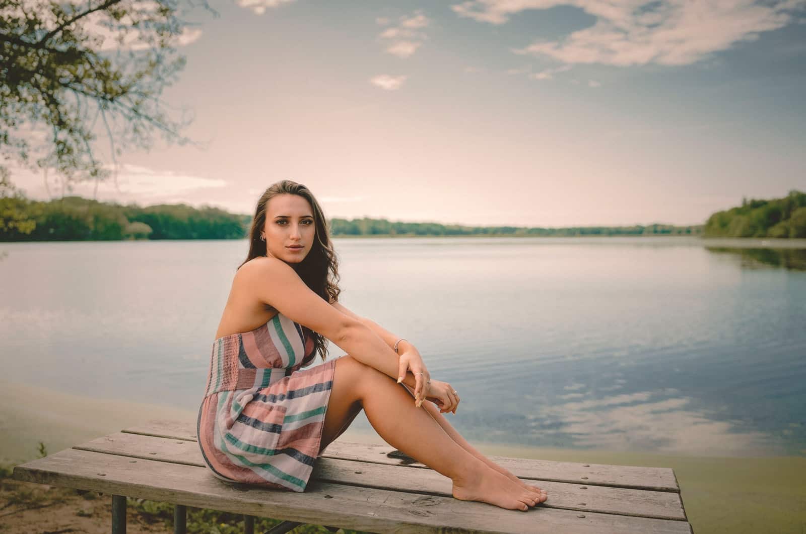 woman sitting on a bench in front of a lake