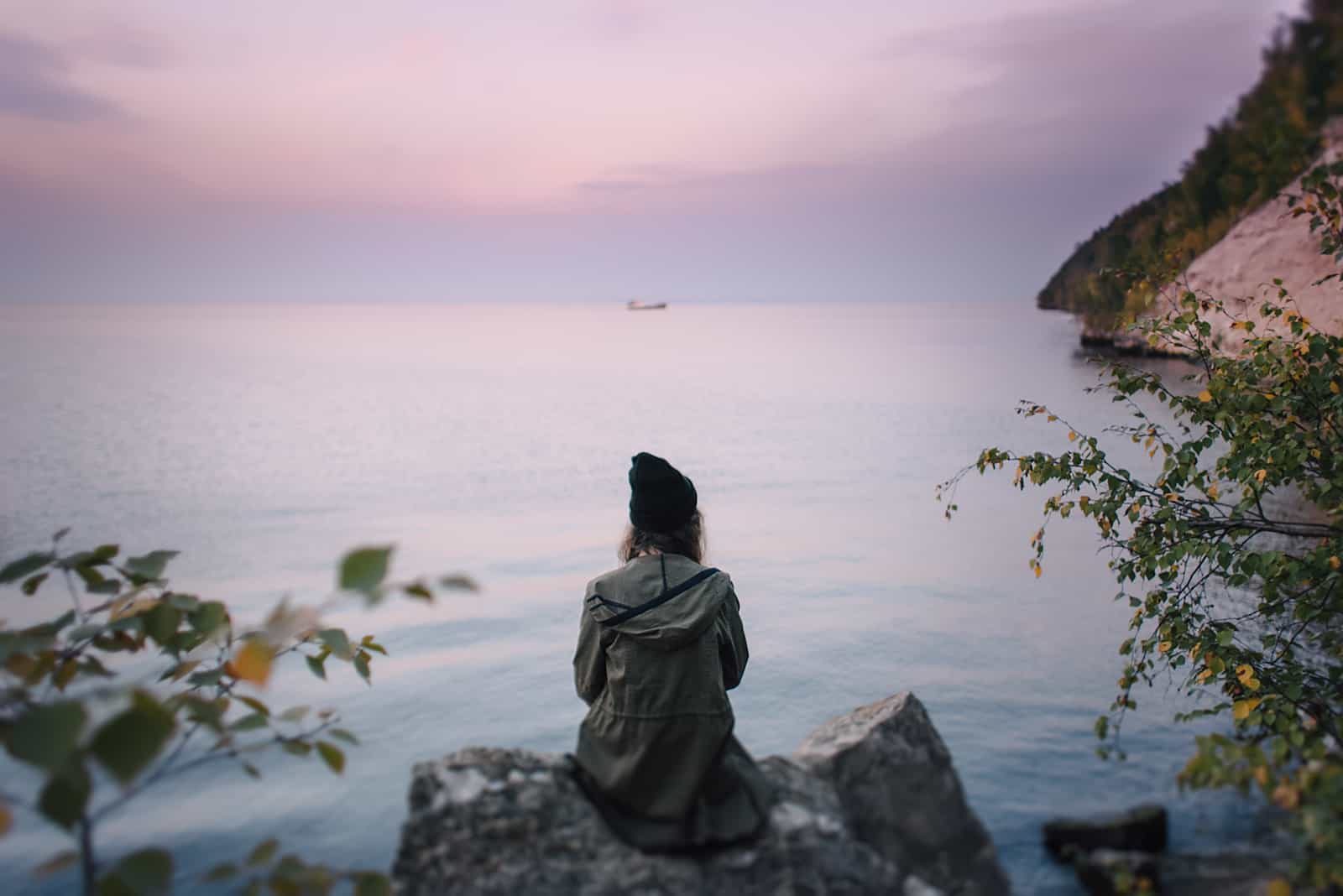 woman sitting on rock by sea