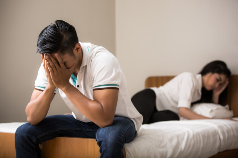 couple sitting on bed after fight