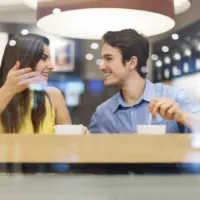 smiling man and woman are sitting in a cafe and talking