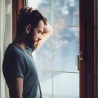 sad man standing by the window