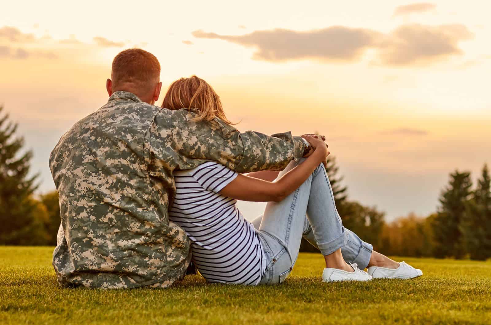 Coppia di militari seduta all'esterno che si abbraccia