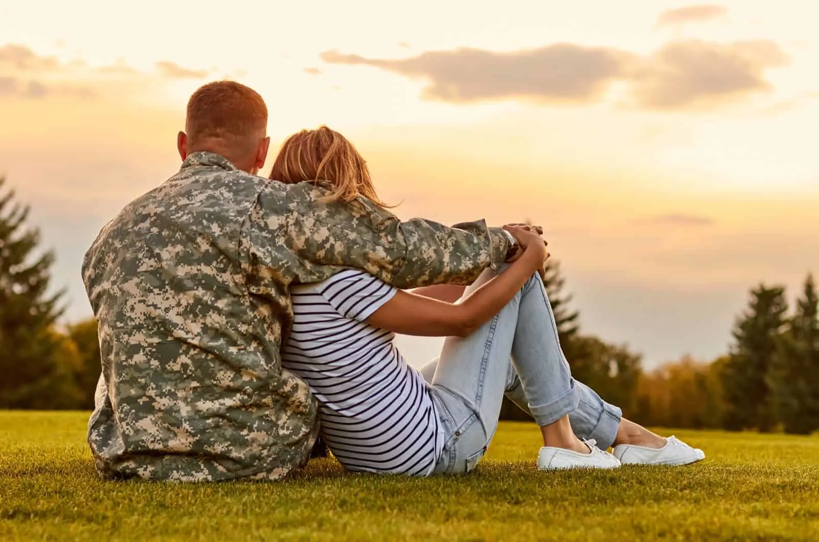 Military couple sitting outside hugging