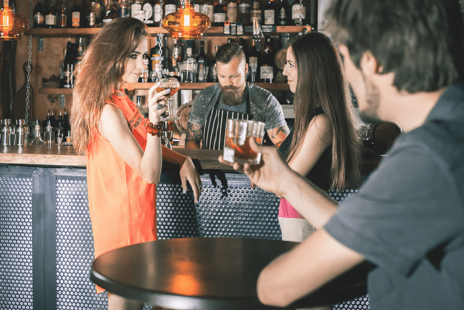 um homem brinda a uma bebida com uma mulher que está atrás de um trenó com um amigo