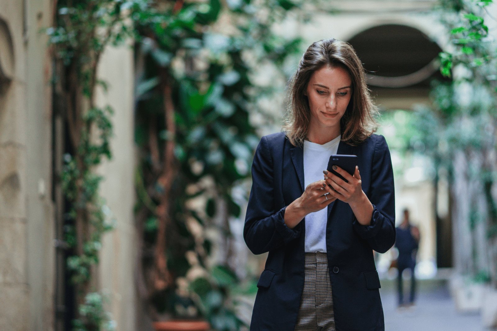 a woman is standing on the street and typing on the phone