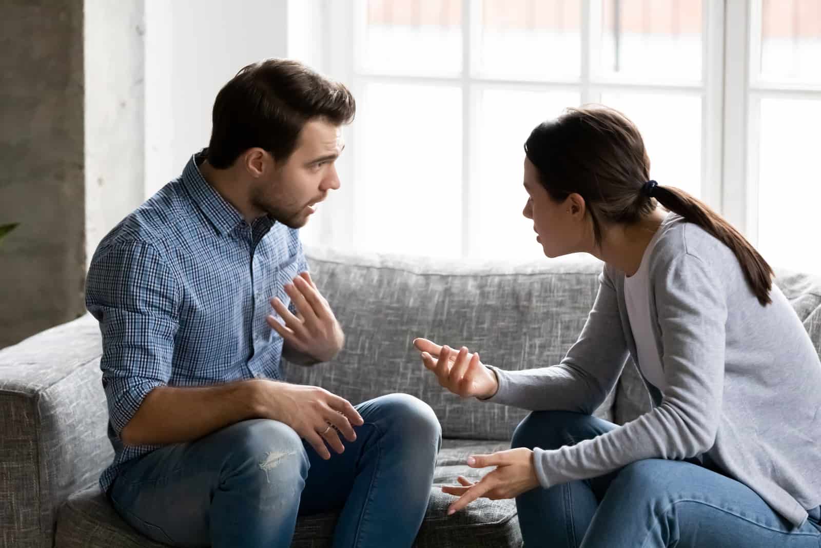 casal a discutir no sofá de casa