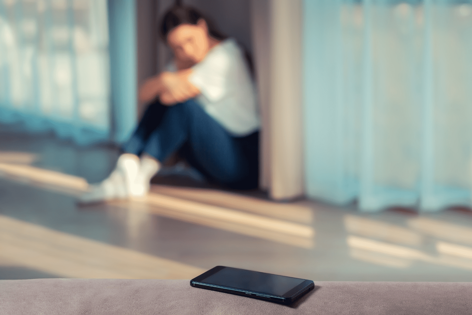 disappointed woman sits on the floor and looks at the phone